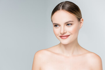 smiling young woman with makeup looking away isolated on grey