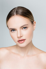 young woman with makeup looking at camera isolated on grey