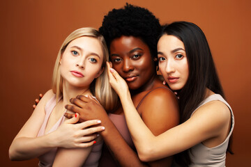 Obraz premium young pretty asian, caucasian, afro woman posing cheerful together on brown background, lifestyle diverse nationality people concept
