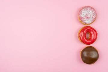 The tasty glazed donuts lie on a pink background