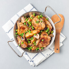 Chicken stew with potatoes, mushrooms and green peas, in metal pot, top view, square format