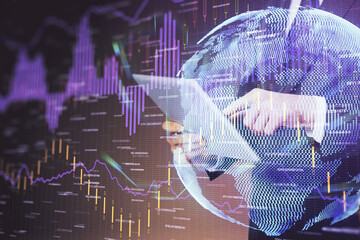 Double exposure of man's hands holding and using a digital device and forex graph drawing. Financial market concept.