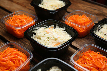 Plastic containers with tasty vegetable salads on wooden table, closeup. Food delivery service