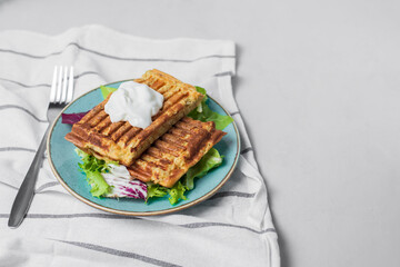 Delicious vegetarian cabbage waffles with cream on light background. Served with towel, salad mix on blue plate. Healthy diet breakfast idea. Simple recipe, copy space