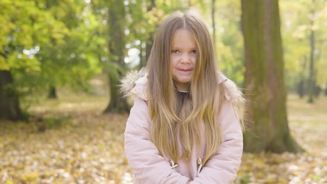 Cute little Caucasian girl applauds to the camera with a smile in a park
