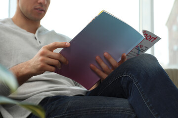 Man reading sports magazine indoors, closeup view