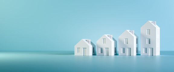 Fototapeta Which size of house can you afford? Concept shot: four differently sized models of houses on a blue background. Copy space available, web banner format obraz