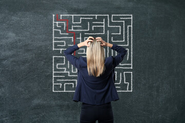 Businesswoman looking at chalkboard with illustration of maze