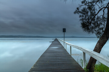 Rainy day sunrise waterscape with wharf