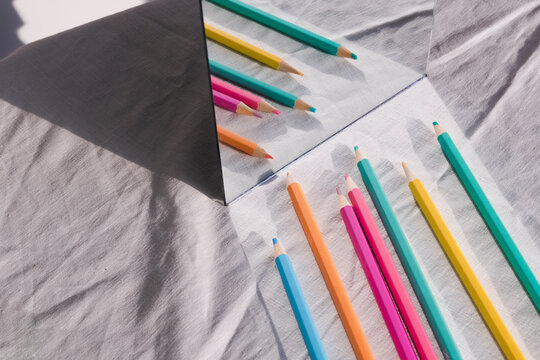 High Angle View Of Colored Pencils On Table By Mirror
