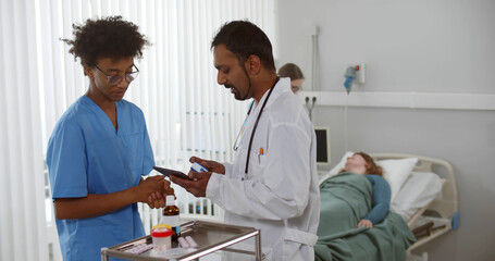 Multiethnic medical team with digital tablet examining female patient in hospital ward