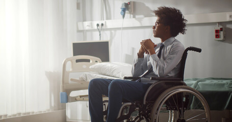 Young disabled afro-american man sitting in wheelchair in hospital ward