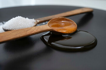 Honey close up, on a wooden spoon, with sugar on the background
