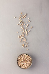 Legumes in bowl and scattered in the background, chickpeas in a plate on a gray background, top view, copy space