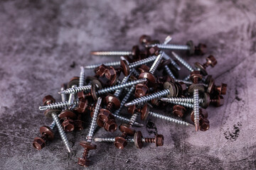 The brown roof screws lie on a gray table in close-up. - 421493351