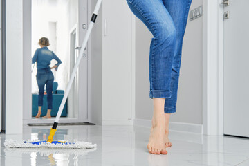 Barefoot female legs leaning to flat wet mop