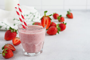 Strawberry smoothie or milkshake with berries and oatmeal in glass jar on gray or white concrete...