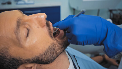 Obraz na płótnie Canvas dentist examining teeth of patient with mouth mirror
