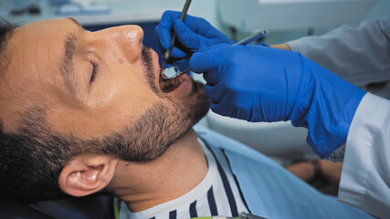 dentist examining teeth of man with mouth mirror and dental probe