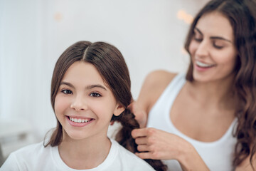 Mom braiding her happy daughters braids