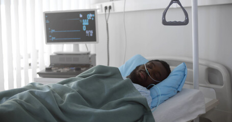 Portrait of afro-american man in coma dying in hospital bed with heart rate falling on ecg monitor