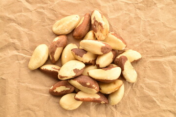 Several delicious organic Brazil nuts on brown paper, close-up, top view.