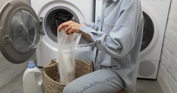 Woman puts clothes into a laundry bag