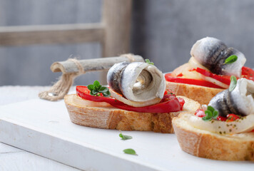 Summer sandwich with marinated anchovies and seasonal veggies on white wooden tray. Mediterranean diet.