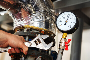 Repair work in an industrial boiler room. A wrench in the hand of a plumber against the background...
