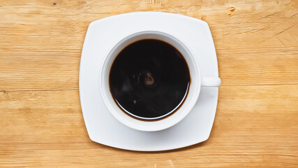 top view of black coffee in white cup on wooden table