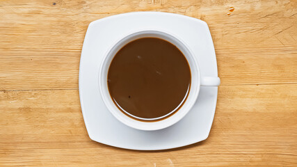 top view of hot chocolate drink in white cup on wooden surface