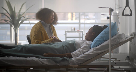 African woman visiting sick best friend in hospital