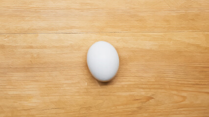 Top view of white chicken egg on wooden table