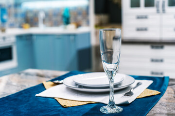 Table setting for one person. Wine glass and plates on the background of the kitchen set. Festive dinner at home. No people. Foreground