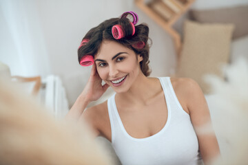 Beautiful young smiling woman in hair curlers
