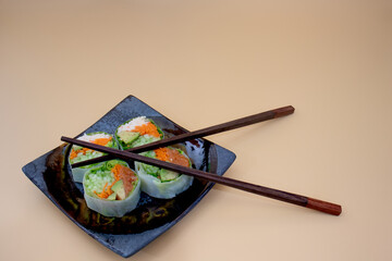 Fototapeta na wymiar Close up of Japanese rice paper sushi roll and crossed chopsticks