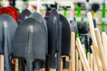 Metal shovels with a wooden handle are sold in the store. Close-up