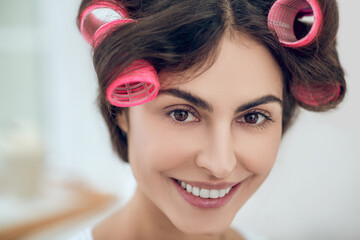 Close-up face of beautiful young woman in hair curlers