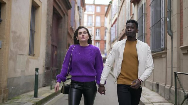 Young interracial couple walking holding hands. Modern millennial couple