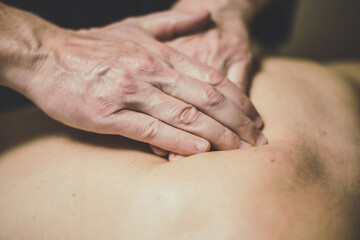Soft focus view of man massaging a woman in a wellness center. Oiled hands on a body relaxing the muscles and relieve tension.  .Olystic xercise for calm and clear your mind. Health well-being concept