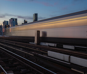 Fototapeta premium Moving train on city skyline background, with long exposure trail perspective 