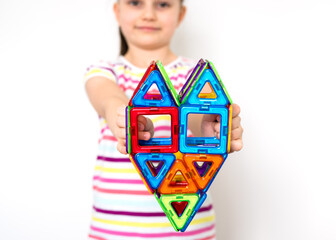 Kid plays with a magnetic constructor toy. A little child girl is playing with colorful blocks....