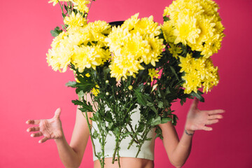 Stylish woman in hat on pink red background throwing to camera large bouquet of yellow asters, spring mood, happy emotions isolated space