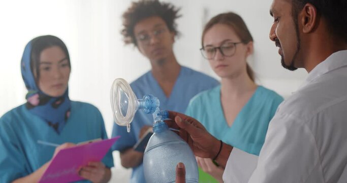 Indian doctor showing breathing bag to group of diverse interns