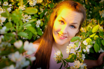 Fototapeta premium Beautiful woman with long hair walking in the park with blooming apple trees