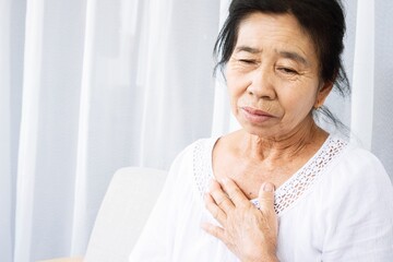 old Asian woman having problem with shortness of breath, difficult breathing hand touching her chest