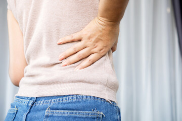 woman suffering from lower back pain, hand holding right side back pain