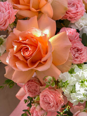 A bouquet of beautiful peach flowers in a box stands on a chair in a flower shop. A composition of roses, white mattiola and chrysanthemum. A gentle gift for a holiday
