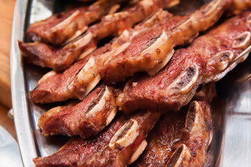 Grilled meat ribs on a metal tray. Meat steak. Close-up. Macro. Defocus. Blur