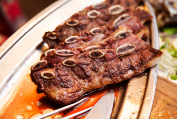 Grilled juicy fried meat ribs with blood on a metal tray. Steak. Defocus, blur